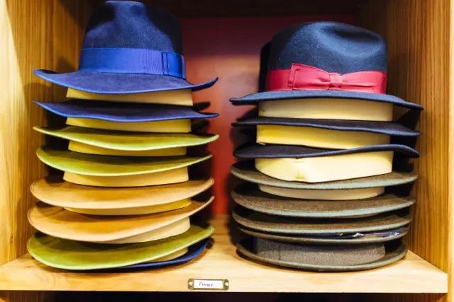 Two piles of hats on a shelf in a store