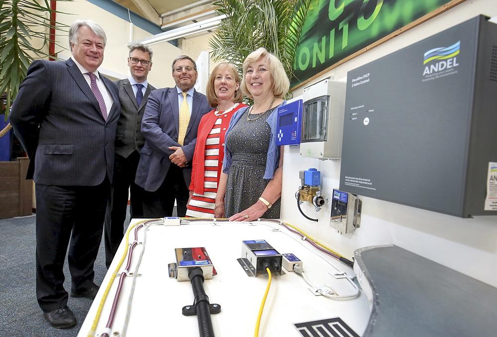 Two women and three men stood next to electrical equipment