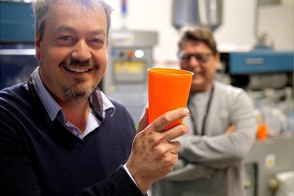 Bockatech CEO holding up a plastic moulded product to the camera, with one of his technician colleagues in the background