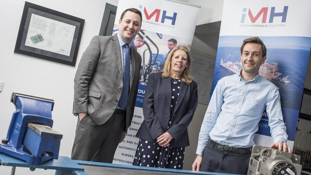 2 men and a woman stood in an office behind some hydraulics equipment with iMH pop up banners in the background