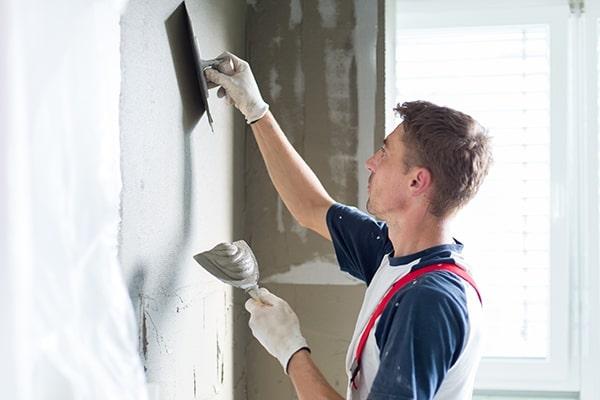 Plasterer renovating indoor walls and ceilings with float and plaster