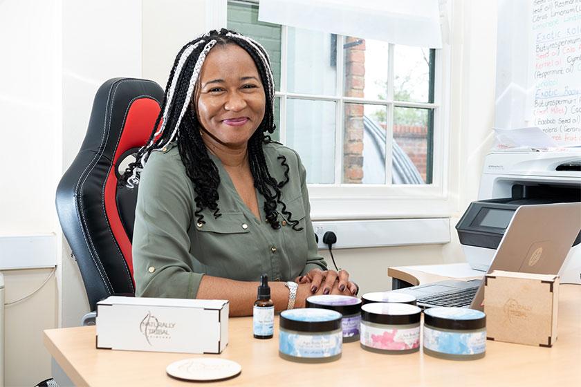 A women sat at a desk showing the Naturally Tribal Skincare products