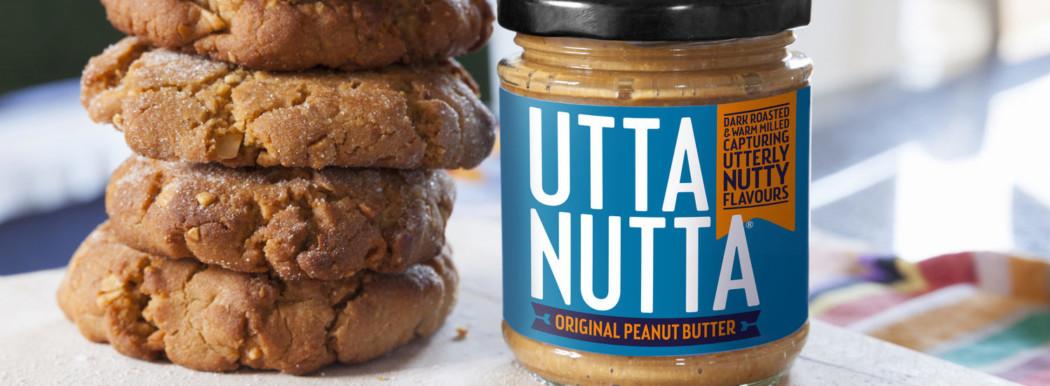 A jar of Utta Nutta Peanut Butter next to a stack of 4 cookies