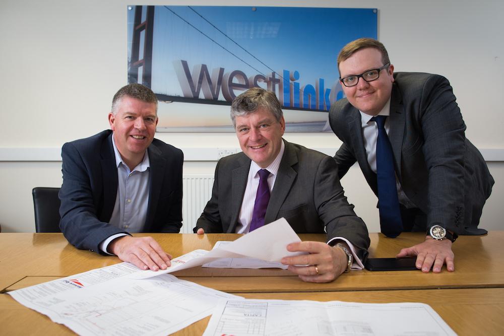 Three men from Westlink Joiners and Locksmiths sat around table holding papers