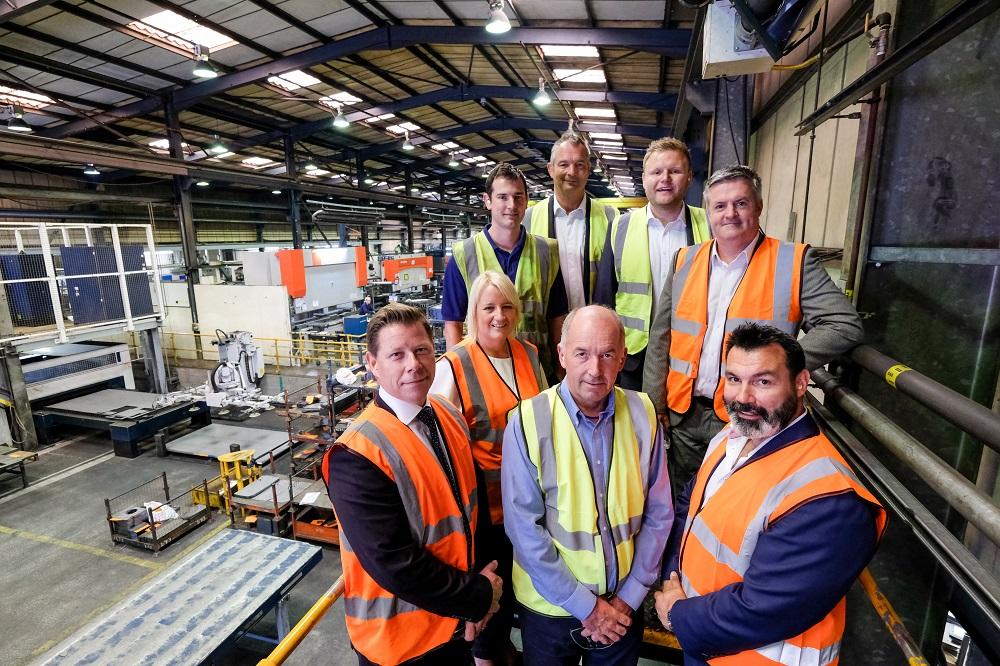 A group of employees from Newfield Fabrications Limited stood in Hi Vis jackets in a warehouse