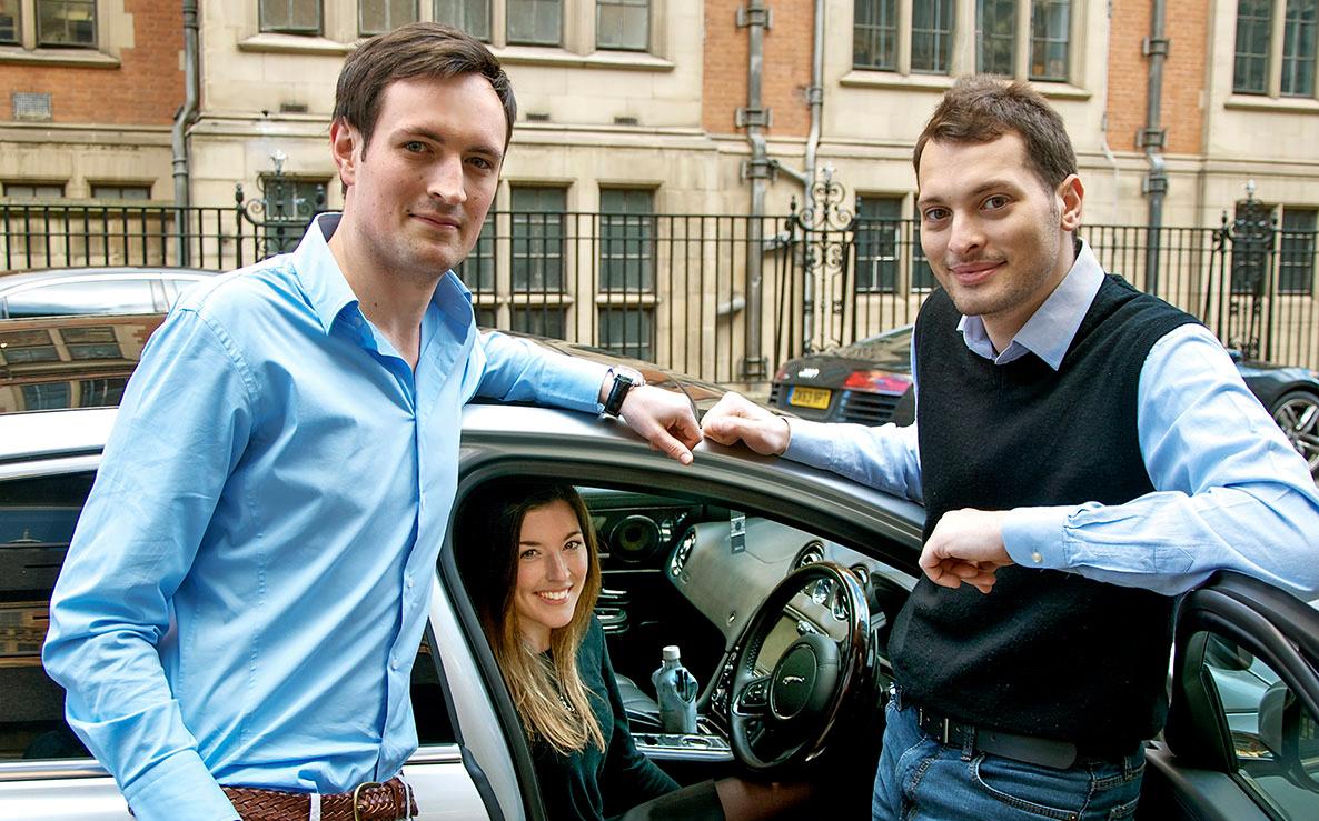 A woman sat in a car with 2 men stood next to her