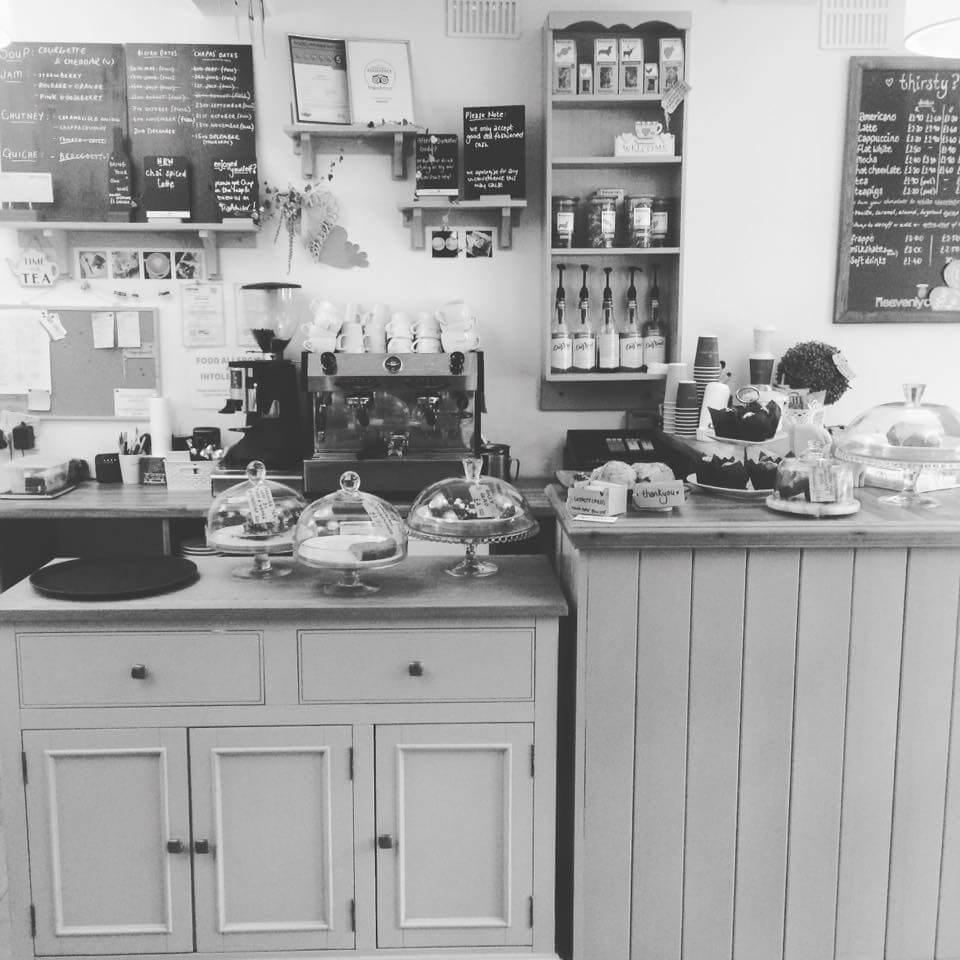 A coffee shop counter with cakes, coffee machine and menu